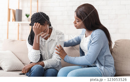 Friendship And Support Concept. Young black woman supporting her depressed friend sitting on sofa at home 123053526