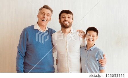 Cheerful Man, His Son And Elderly Father Embracing Standing Over White Wall Indoor. Male Generations Family Concept. Panorama 123053553