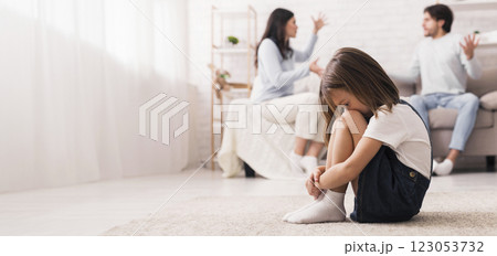Family Conflict. Little girl crying after parents quarrel at home, sitting alone with her head down, hiding her face in knees, selective focus Family Conflict. Little girl crying after parents quarrel at home, sitting alone with her head down, hiding her face in knees, selective focus 123053732