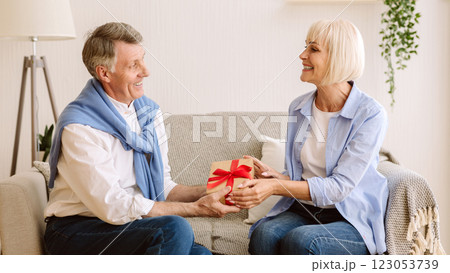 Gift with love. Mature man giving present to wife, congratulating with birthday 123053739