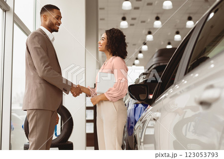 Buying Car Concept. Afro Businessman Handshaking With Manager Girl Standing Near Auto In Automobile Dealership Shop. Free Space Buying Car Concept. Afro Businessman Handshaking With Manager Girl Standing Near Auto In Automobile Dealership Shop. Free Space 123053793