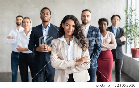 Successful Latin Businesswoman Standing In Front Of Business Team Posing In Modern Office, Smiling To Camera. Female Entrepreneurship And Leadership, Career Growth And Success. Selective Focus 123053910