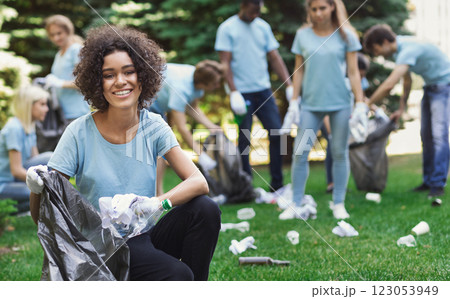 Volunteering, charity and clean environment concept. Happy black woman and group of volunteers with garbage bags cleaning area in park, copy space 123053949