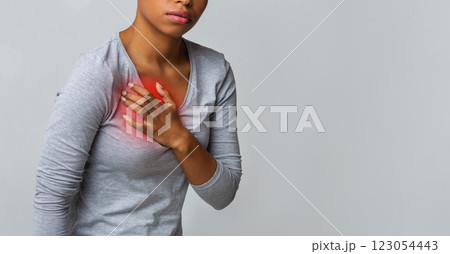 Cropped of afro woman suffering from acid reflux or heartburn, symptomatic indigestion or gastritis disease, grey background 123054443