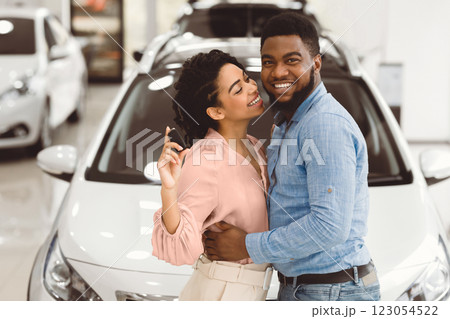 Afro Couple Showing New Car Key Hugging Standing In Dealership Store. Buying Automobile Concept. Afro Couple Showing New Car Key Hugging Standing In Dealership Store. Buying Automobile Concept. 123054522
