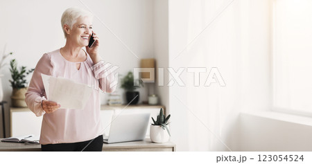 Aged cheerful business woman consulting clients by phone from home, holding papers, free space 123054524