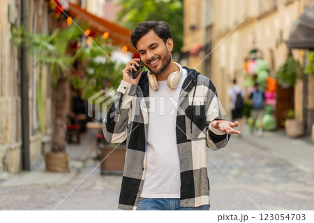 Indian young man tourist on smartphone, chatting with friend while walking in the city street Indian young man tourist on smartphone, chatting with friend while walking in the city street 123054703