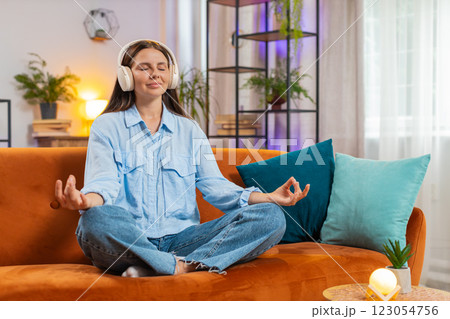 Young woman listening music, breathes deeply meditating with concentrated thoughts peaceful at home 123054756