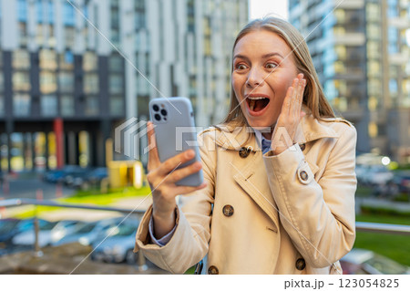 Caucasian mature woman looking shocked while reading good news on smartphone on downtown city street 123054825