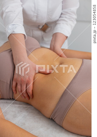 Cosmetologist massagist making woman spa anti-cellulite treatment massage scrubbing belly with scrub 123054858