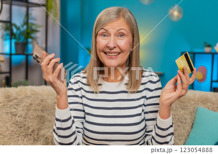 Mature woman shopping online on smartphone entering credit card info satisfied with purchase at home Mature woman shopping online on smartphone entering credit card info satisfied with purchase at home 123054888