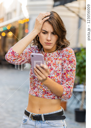 Surprised young woman use smartphone loses, bad news, fortune loss, fail outdoors in city street Surprised young woman use smartphone loses, bad news, fortune loss, fail outdoors in city street 123056009