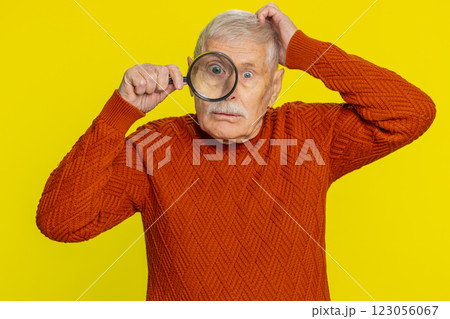 Senior old man holds magnifying glass near face looking at camera with big zoomed eye, analyzing Senior old man holds magnifying glass near face looking at camera with big zoomed eye, analyzing 123056067