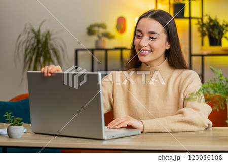 Woman freelancer opens laptop working sends messages business email watching movies at home table 123056108