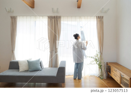 リビングでカーテンを開ける女性 リビングでカーテンを開ける女性 123057513