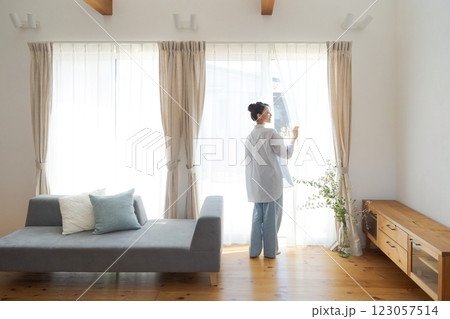 リビングでカーテンを開ける女性 123057514
