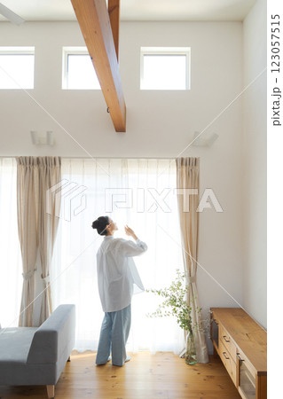 リビングでカーテンを開ける女性 123057515