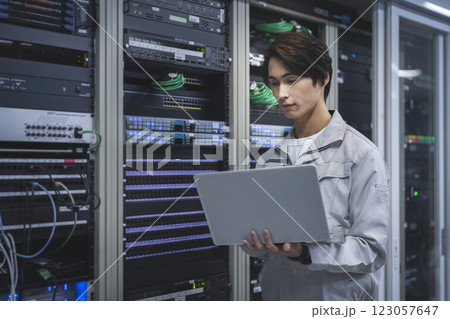 サーバーエンジニア　イメージ　ノートパソコンを持って作業をするエンジニア 横顔 123057647