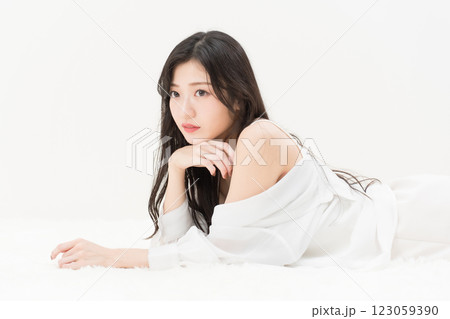 ビューティーイメージ　白シャツを着て頬付を付いて寝そべる若い女性 　　アンニュイ 123059390