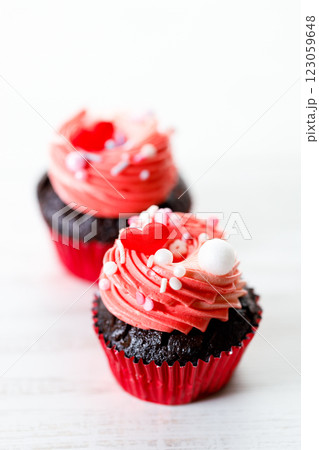 Chocolate cupcakes with pink cream and heart shaped sprinkles. 123059648