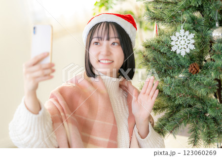 クリスマスツリーの前でスマホで写真を撮る女性 123060269