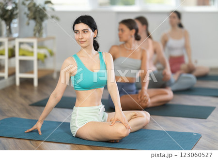 Young girl teaches yoga lesson, shows students technique of performing padmasana asana 123060527
