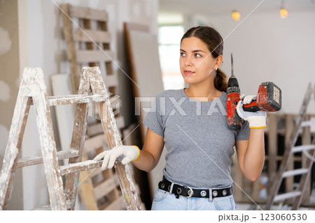 Smiling woman holding drill, repair works in apartment 123060530