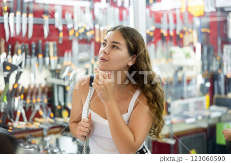 Female buyer holds in hands tests edged weapons in memorable gifts shop 123060590