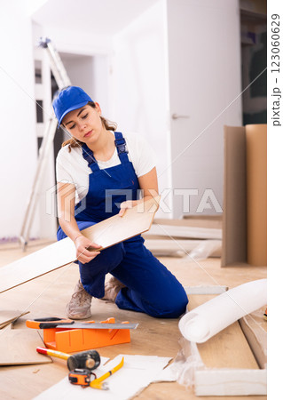 Female builder checking laminate planks before installation Female builder checking laminate planks before installation 123060629
