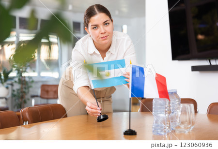 Young female assistant putting up french and argentinian flags on table for international negotiations 123060936