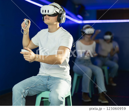 Guy playing game in virtual reality glasses in front of friends 123060959