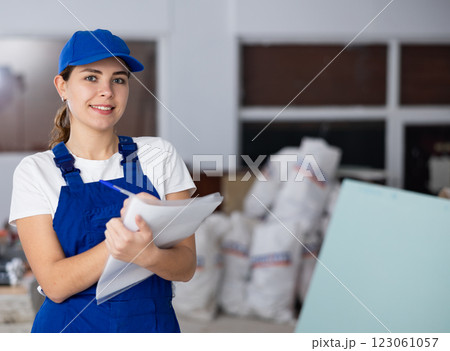Positive young female builder contractor inspecting room and taking notes 123061057