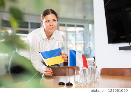 Woman secretary prepares an office for negotiations - she places flags of France and Ukrain table Woman secretary prepares an office for negotiations - she places flags of France and Ukrain table 123061090