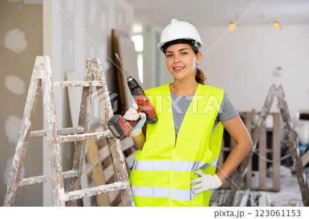Female foreman in protective yellow vest and hard hat with screwdriver in hand 123061153