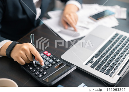 Finance bank tax expense accounting budget money businessman hand use calculator Financial calculate accountant close up calculator with graph chart write office desk Business expense analysis saving 123063265