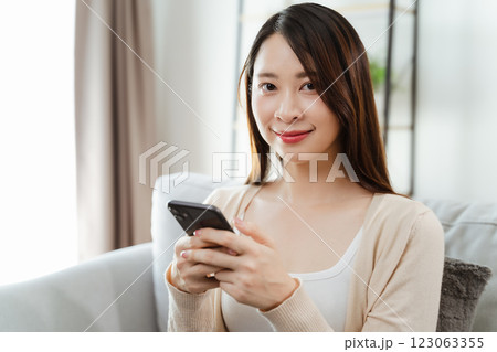 Beautiful young woman holding and using a smartphone, using social media, shopping online 123063355