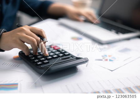 Finance bank tax expense accounting budget money businessman hand use calculator Financial calculate accountant close up calculator with graph chart write office desk Business expense analysis saving 123063505