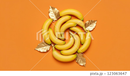 Creative banana arrangement with gold leaves on vibrant orange background 123063647