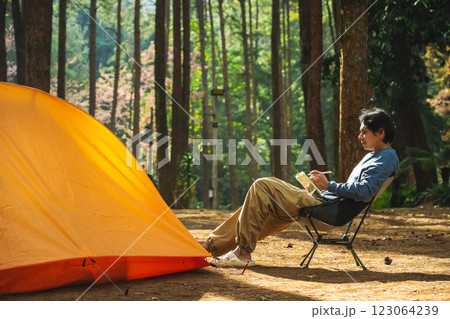 solo traveler in nature concept with asian man camping and work online with pink cherry blossom and pine tree in springtime season solo traveler in nature concept with asian man camping and work online with pink cherry blossom and pine tree in springtime season 123064239