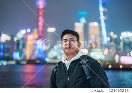 Man traveler visiting in Shanghai, China. Male Tourist with backpack sightseeing Shanghai view of Lujiazui in The Bund of Shanghai at night. landmark and popular for tourism attractions 123065258