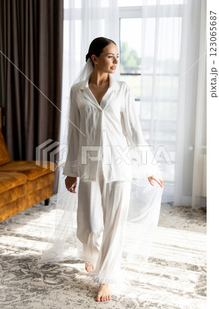 Bride wearing white pajamas and veil getting ready for wedding ceremony 123065687