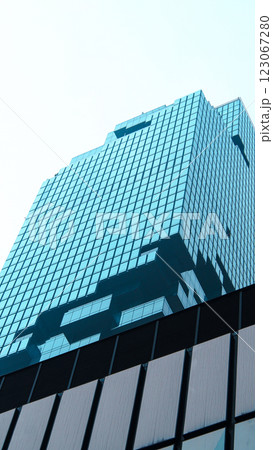 A modern high-rise building with a blue-tinted glass facade, featuring stacked and protruding sections that create a dynamic architectural form A modern high-rise building with a blue-tinted glass facade, featuring stacked and protruding sections that create a dynamic architectural form 123067280