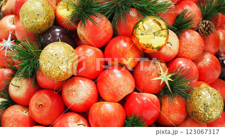 A festive arrangement of red apples, golden baubles, pine branches, and star ornaments, creating a warm and elegant holiday display. 123067317