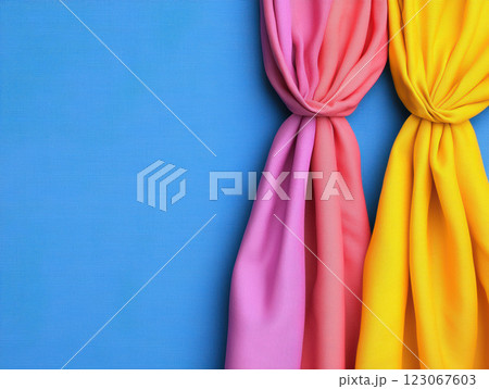Vibrant pink and yellow fabric drapes against blue background, creating cheerful atmosphere 123067603