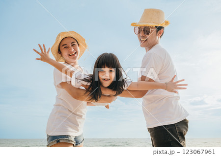 Asian family is playing together in fly action on the beach, Happy parents mother and father holding their child daughter spread arms out like airplane wings, family is enjoying their summer time Asian family is playing together in fly action on the beach, Happy parents mother and father holding their child daughter spread arms out like airplane wings, family is enjoying their summer time 123067961