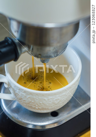 Fresh coffee pouring from coffee machine into a white textured cup. High quality photo 123068827