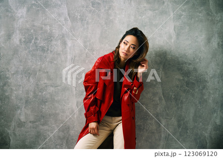 Fashionable confident woman wearing red coat and stylish casual outfit posing at studio. Fashionable confident woman wearing red coat and stylish casual outfit posing at studio. 123069120