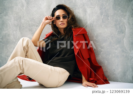 Fashionable confident woman wearing red coat and stylish casual outfit posing at studio. Fashionable confident woman wearing red coat and stylish casual outfit posing at studio. 123069139