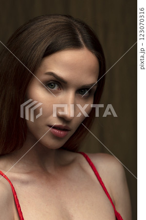 portrait of a beautiful young woman in a red dress, studio shot on a dark background 123070316