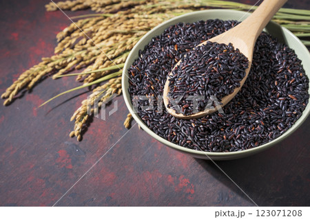 Beautiful black-rice in a bowl with wooden spoon and ears of rice on red table Beautiful black-rice in a bowl with wooden spoon and ears of rice on red table 123071208